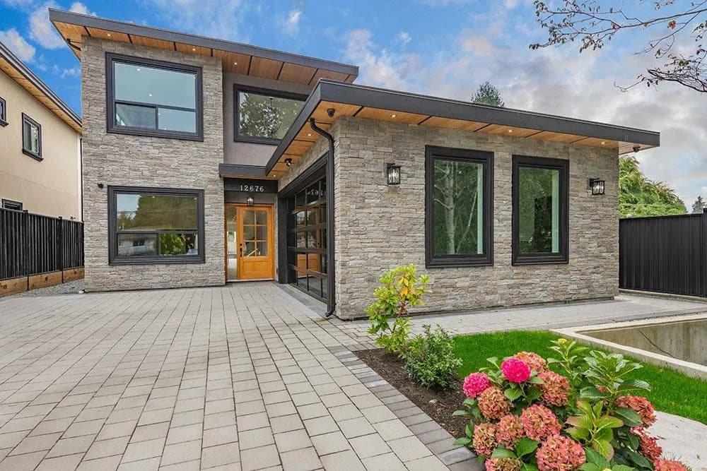 Front exterior of the custom two-level home at 12676 25 Avenue, Crescent Beach, South Surrey BC — stone and stucco facade, paver driveway, built by Pro Construction Group
