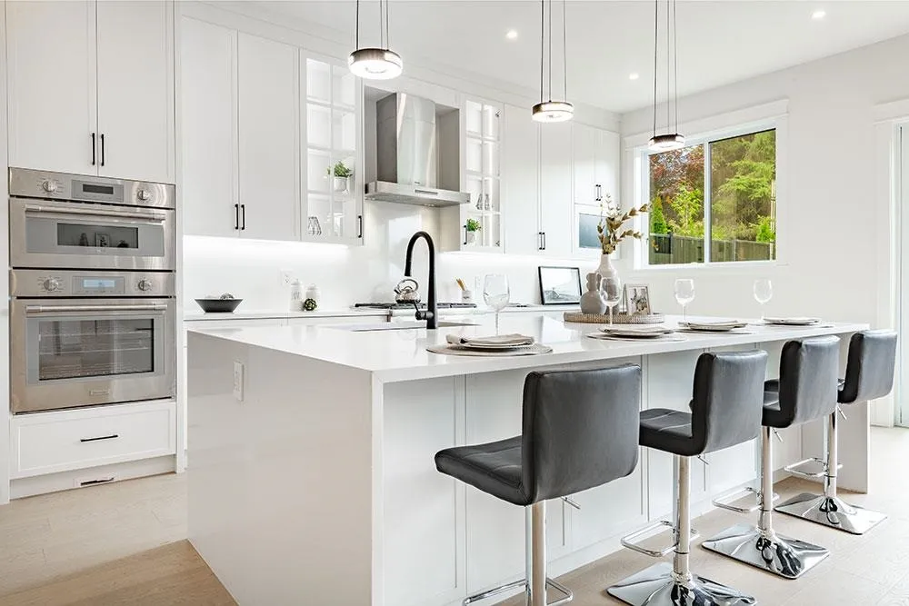 Chef’s kitchen with large quartz island, Thermador double convection ovens and hood in the Crescent Beach custom home at 12676 25 Avenue, South Surrey BC