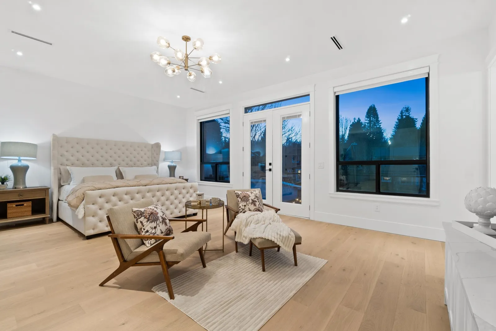 Primary bedroom with private balcony doors and chandelier in the custom home at 12686 25 Avenue, Crescent Beach, South Surrey