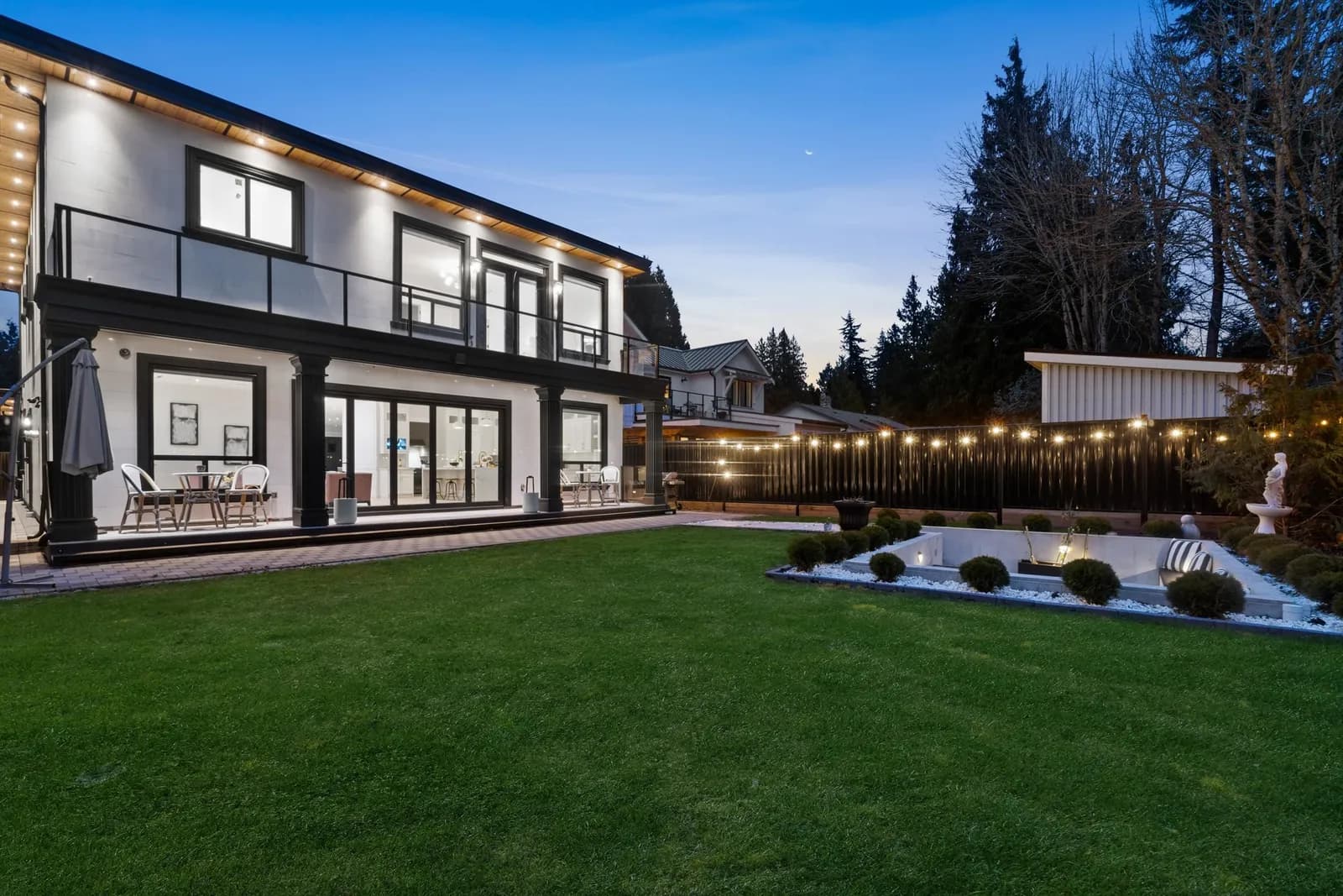 Rear elevation at dusk with the 15-foot nano door open to the patio and upper balconies, 12686 25 Avenue, Crescent Beach, South Surrey BC